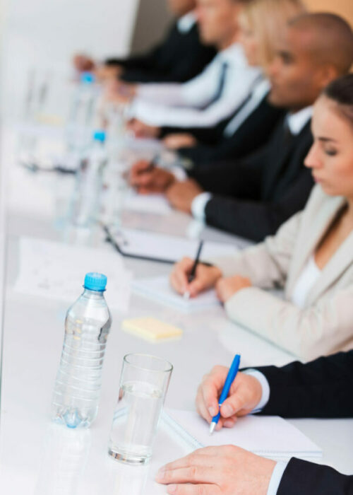 Business conference. Side view of business people writing something in their note pads while sitting in a row